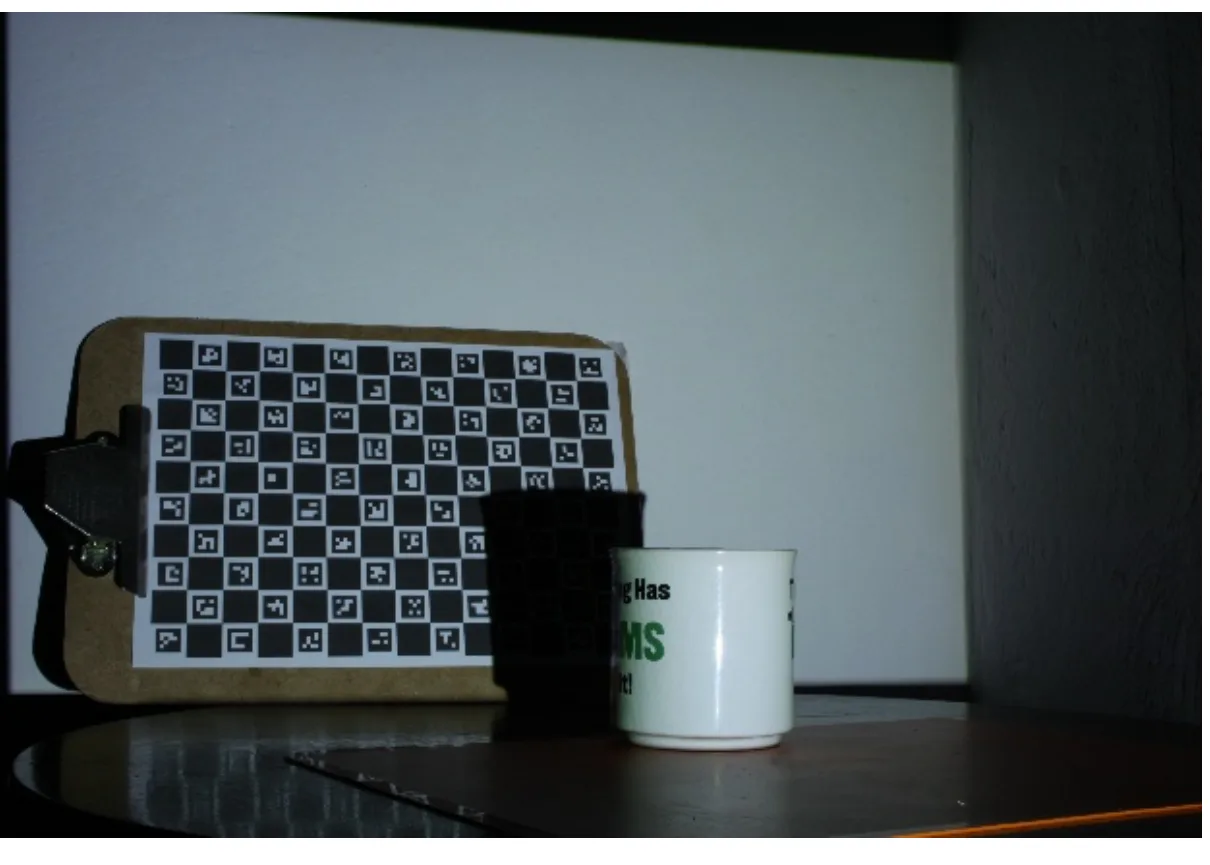 A checkerboard-with-markers board propped on a clipboard next to a mug, photographed under uneven lighting.