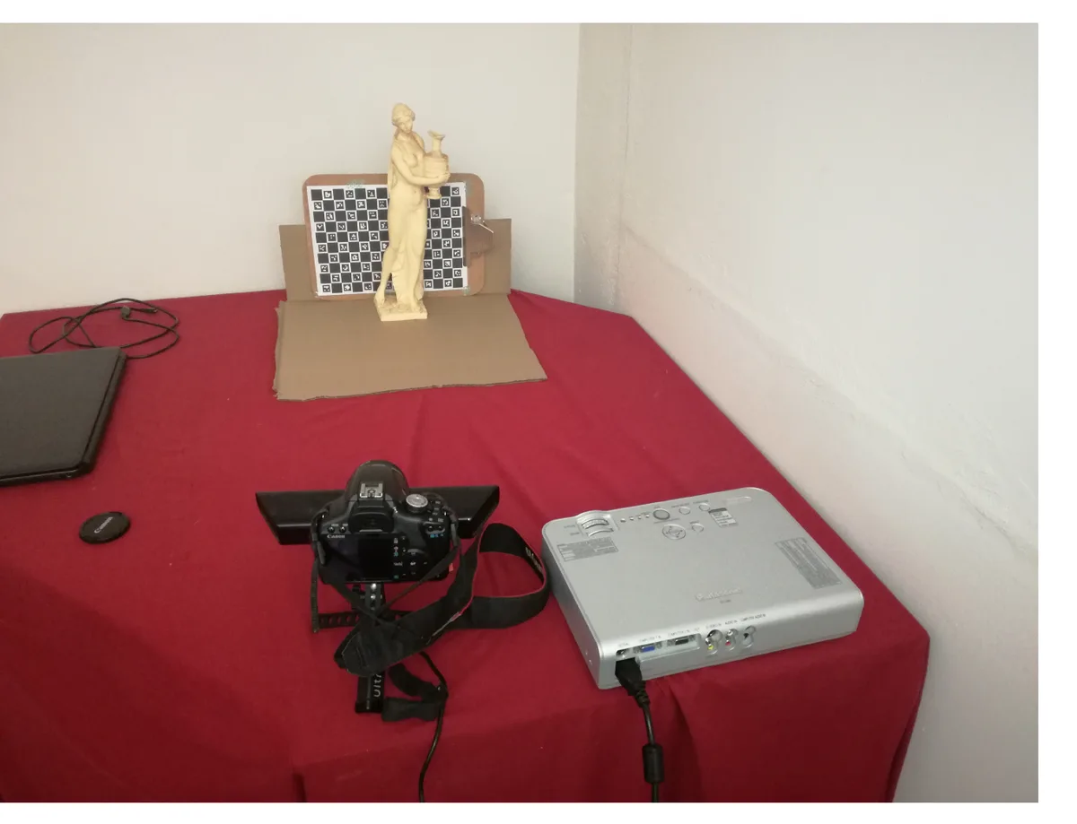 The scan target: a small plaster statue in front of a ChArUco calibration board, with the camera and projector visible in the foreground